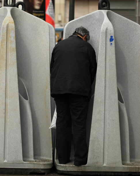 A man is peeing in a public open air loo in Amsterdam. These makeshift plastic urinals offer no cover and are source of nasty smell as well as eyesore. Lack of flushing and hand washing is worrisome. - Photo, Image
