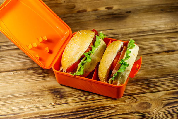 Обеденная коробка с двумя домашними чизбургерами на деревянном столе
 - Фото, изображение