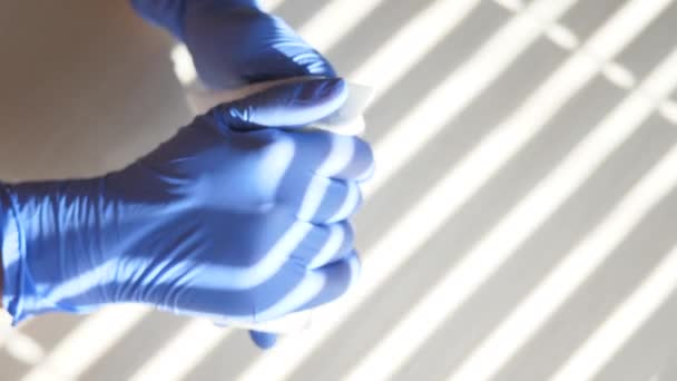 Egy kesztyűs orvos fertőtleníti a kezét antimikrobiális törlőkendővel. Koronavírus. Asztali, irodai, kórházi vagy egyéb törlőkendők fertőtlenítése a koronavírus terjedésének megállítására COVID-19 - Felvétel, videó