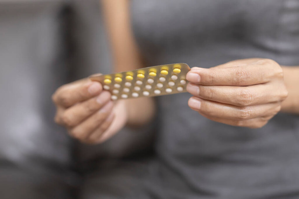 Жінка тримає комбіновану таблетку для пероральних контрацептивів.
. - Фото, зображення