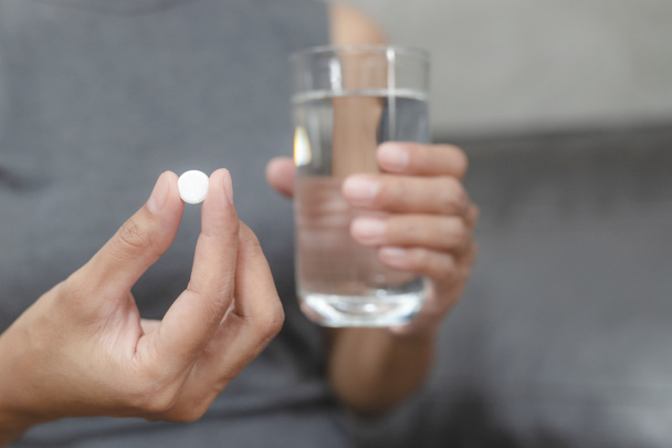 Close-up van de vrouw die pillen inneemt ze giet de pillen uit de fles, het nemen van pijnstiller te verminderen scherpe pijn concept, gezondheidszorg en geneeskunde concept. - Foto, afbeelding