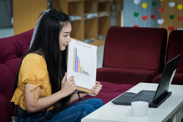 Eine junge Studentin präsentiert ihre Projektstudie während der COVID-19-Pandemie online per Laptop zu Hause. Teenager-Studentin stellt ihre Arbeit online vor. Archivbild. - Foto, Bild