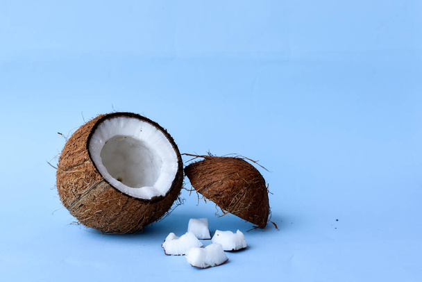 Geknackte Kokosnuss und Schokoladenlöffel auf blauem Hintergrund - Foto, Bild