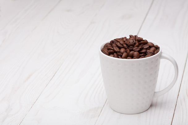 beautiful white coffee cup with coffee beans on wooden background - Foto, immagini