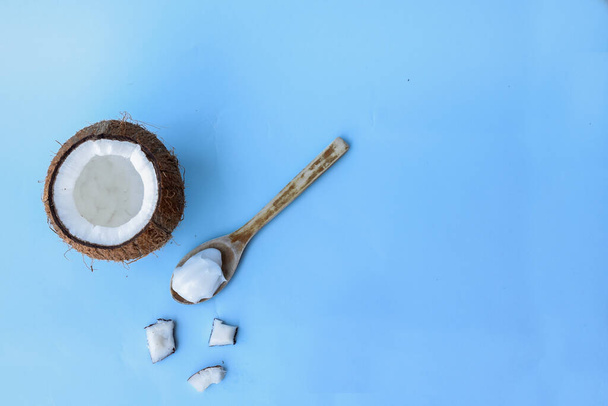 Gebarsten kokosnoot en chocolade lepel op een blauwe achtergrond - Foto, afbeelding