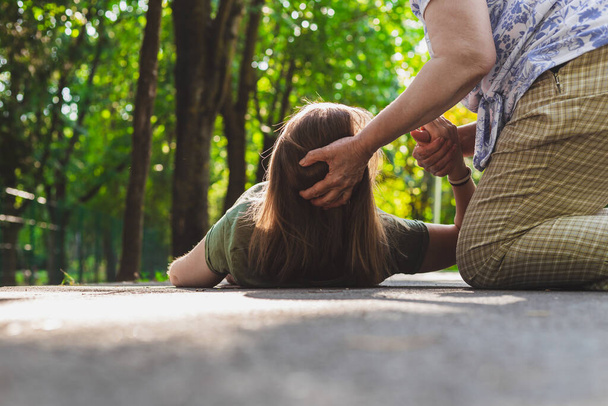 Λιποθύμησε κοπέλα με τη βοήθεια μιας γριάς. Έφηβος προσπαθεί να σταθεί στα πόδια της ενώ λαμβάνει υποστήριξη από έναν ηλικιωμένο - Φωτογραφία, εικόνα
