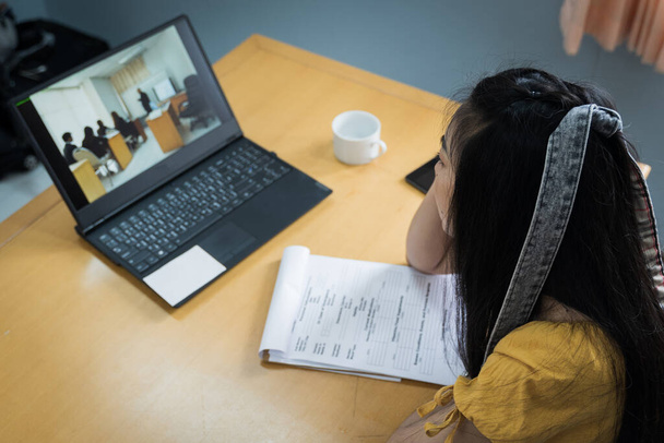Ένας έφηβος σπουδάζει online μέσω φορητού υπολογιστή. Φοιτητής του Πανεπιστημίου κορίτσι παρακολουθεί online μαθήματα και γράφοντας ένα αναλυτικό πρόγραμμα στο σημειωματάριο. Έννοια της εξ αποστάσεως μελέτης, online μάθηση, webinars. Στοκ φωτογραφία. - Φωτογραφία, εικόνα