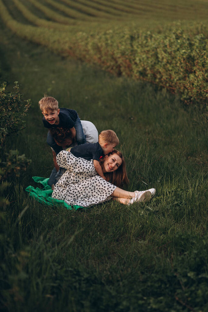 Happy family in nature. Mother, father and two sons are having fun outside the city. - Foto, afbeelding