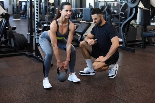 Fitness instructor exercising with his client at the gym - Photo, image