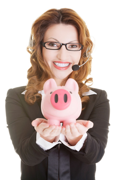 Business woman with headset holding piggy bank - Фото, зображення