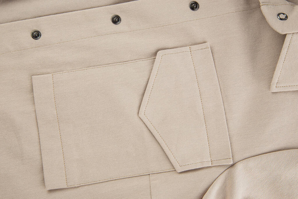 patch bolso com aba em uma camisa bege feita de tecido de algodão grosso
 - Foto, Imagem
