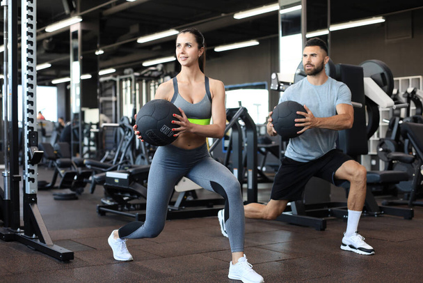 Attractive couple doing fitness with medcine ball at gym - Foto, imagen
