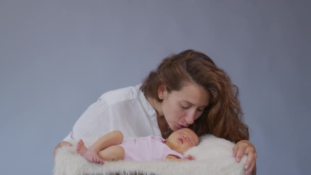 Matka i jej nowonarodzone dziecko. Szczęśliwa matka trzyma swoją nowo narodzoną córeczkę całującą i przytulającą. Zwolniony ruch. - Materiał filmowy, wideo