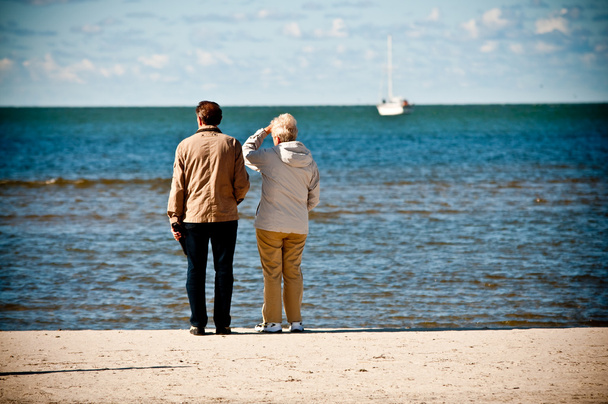 ηλικιωμένο ζευγάρι στην παραλία αναζητούν βάρκα στη θάλασσα - Φωτογραφία, εικόνα