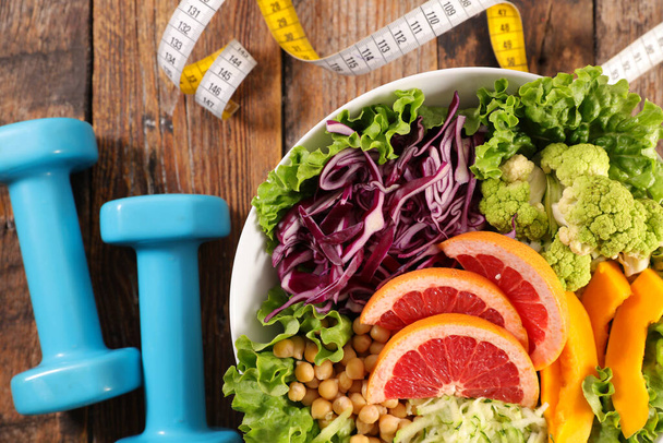 diet food concept with vegetable salad, dumbbell and meter tape - Foto, immagini