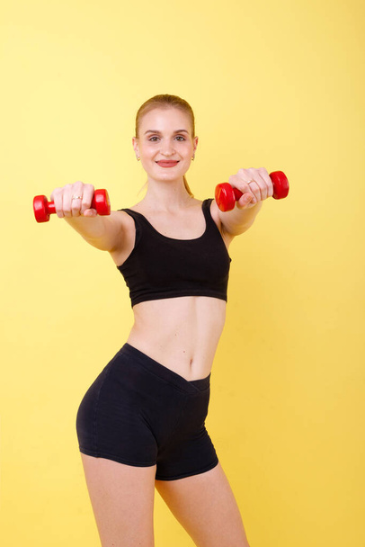 sports girl with dumbbells on a yellow background - Photo, image