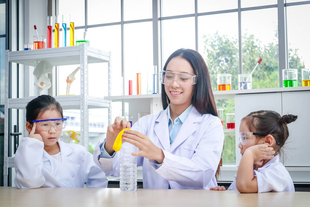 Piękne naukowcy uczą dwie dziewczyny, które są zainteresowane nauką w laboratorium. - Zdjęcie, obraz