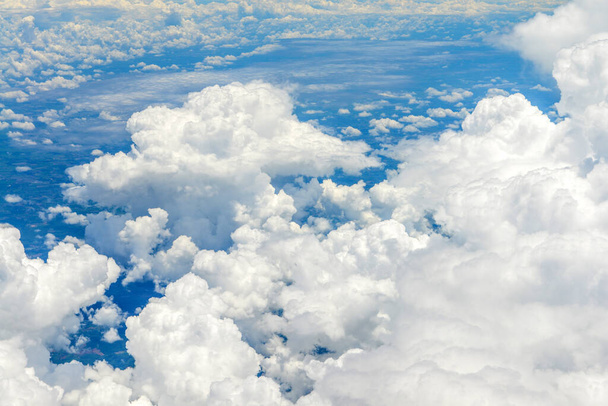 Όμορφη θέα του μπλε ουρανού πάνω από τα άσπρα σύννεφα από το παράθυρο του αεροπλάνου  - Φωτογραφία, εικόνα