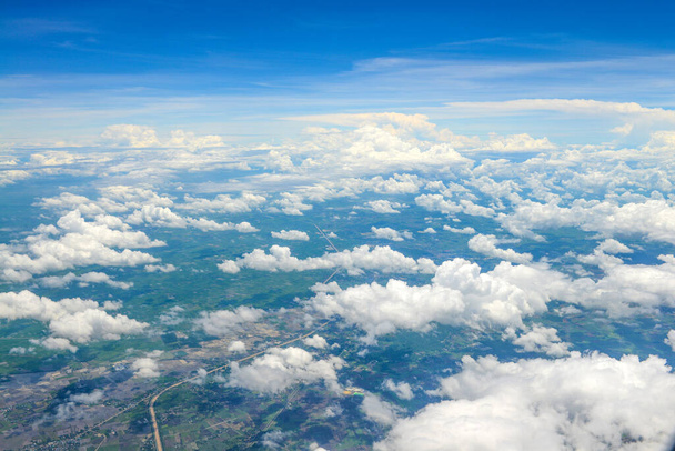 Gyönyörű kilátás kék ég felett a fehér felhők és a szárazföldi háttér repülőgép ablakából - Fotó, kép
