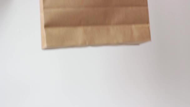 Female hand in a glove holds brown cardboard bag on white background. - Felvétel, videó