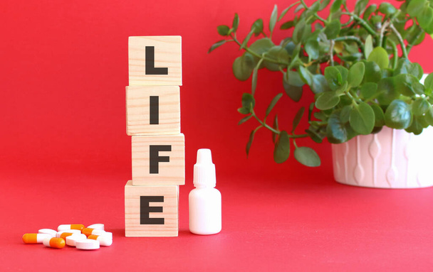 Слово LIFE складається з дерев'яних кубиків на червоному тлі з медичними препаратами. Медична концепція
. - Фото, зображення