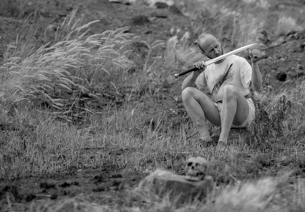 Warlike wanderer in the mountains resting after a battle with a dagger in his hand - Photo, Image