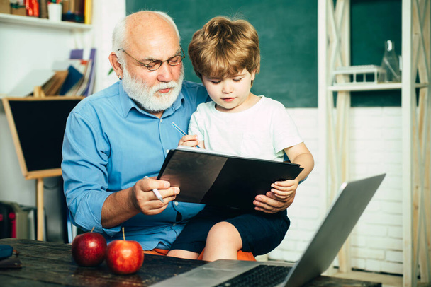 Old and Young. Happy cute clever boy and old tutor with book. Educational process. Family generation and relations concept. Educational process. Grandfather with grandson learning together. - Foto, Imagen