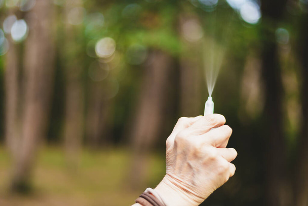 Mão segurando spray nasal na natureza com espaço de cópia. Pessoa que usa a medicina para questões sazonais. Dispositivo médico para reações alérgicas
 - Foto, Imagem