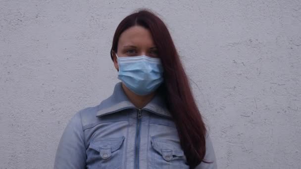 Een vrouw met een beschermend masker kijkt recht in de camera. - Video