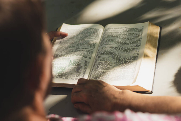 Junge Menschen lesen an einem sonnigen Tag im Freien die Bibel. Friedliche Frau beim Lernen aus dem Heiligen Buch in der Natur. Konzeptbild für Spiritualität - Foto, Bild