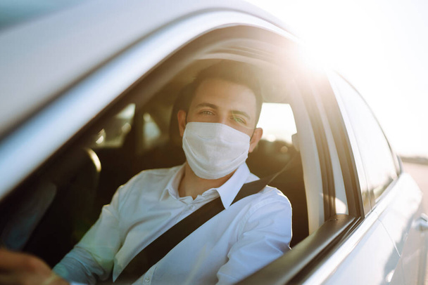 Man driving a car wearing on a medical mask during an epidemic, a driver- taxi in a mask. Covid-2019. - Fotografie, Obrázek