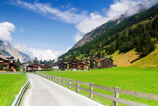 Az aszfaltozott út egy kis faluba a svájci Alpokban. - Fotó, kép