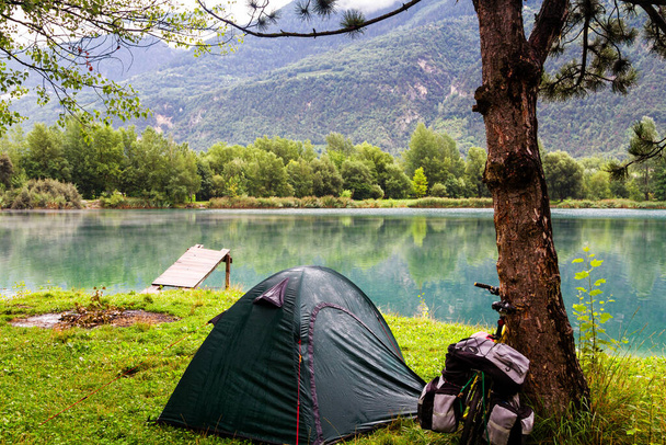 SION, SWITZERLAND - AUGUST 12: Lonely campsite by the lake on a rainy morning in Switzerland Alps near Sion on August 12, 2014. Cycling and camping is a popular way of visiting a country. - Foto, immagini