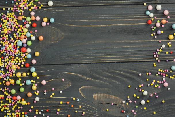 Kleurrijke schuimbal textuur. Kleurrijk polystyreen schuim op een zwarte houten ondergrond - Foto, afbeelding
