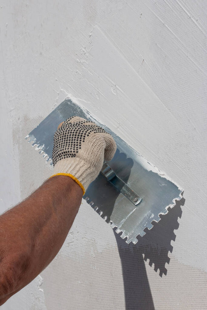 Construtor usando ferramenta de reboco para acabamento de parede
 - Foto, Imagem