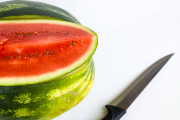 Doce e uma fatia de melancia corte no fundo branco com faca
 - Foto, Imagem