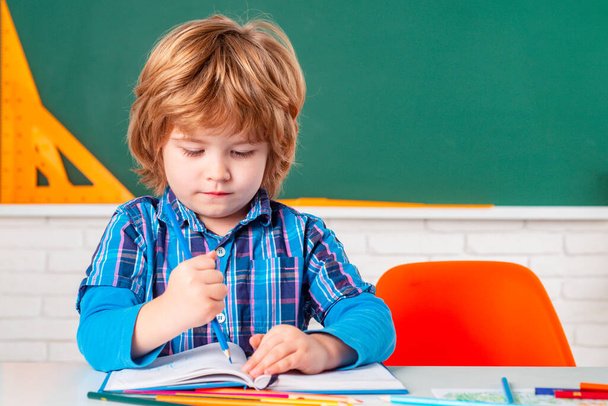 Schoolkid or preschooler learn. Cute child boy in classroom near blackboard desk. Kids from primary school. Happy school kids at lesson. - Photo, Image