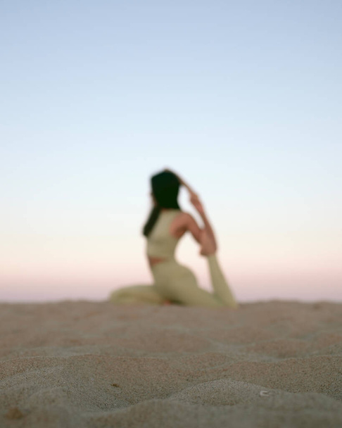 Young woman practicing yoga on the beach during sunset. Stock photo of a girl exercising on the Mediterranean sea. - Foto, afbeelding
