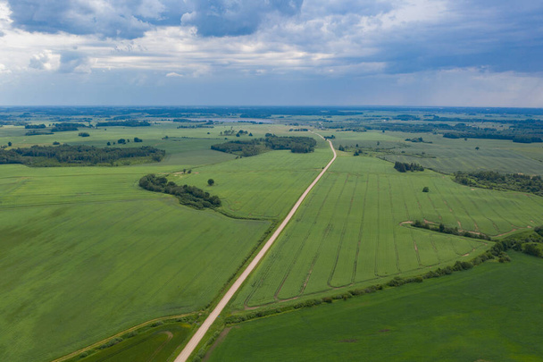Aerial view of gravel road on green farmland fields in summer time - Φωτογραφία, εικόνα