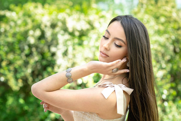 Young woman shows jewelry isolated on spring nature background - 写真・画像