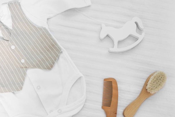 Baby stuff on a white bed. White body, comb and toy horse on a white background.Baby stuff and accessories. Flat lay, top view - Foto, afbeelding