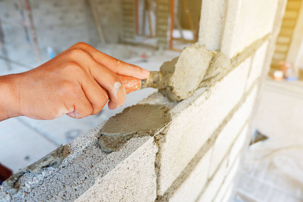 hand van metselaar werkt voor Wandbouw met cement baksteen blok - Foto, afbeelding