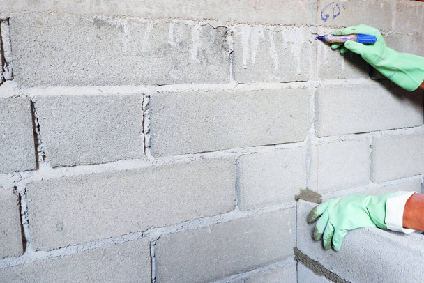İnsan tuğla ustası beton tuğla duvar inşaatının seviyesini bulmak için işaret koyuyor.. - Fotoğraf, Görsel