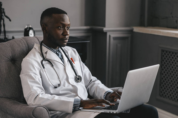 un medico afroamericano fornisce consulenze telemedicine attraverso la trasmissione di informazioni mediche attraverso canali di telecomunicazione - Foto, immagini