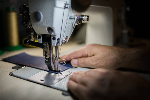 A man sews from leather on a sewing machine. Hands and sewing.  - Foto, Bild