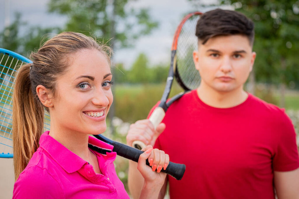 Tennispelaajat muotokuva ulkona. Pari tai sekoitettu kaksinkertainen tennis kumppanit ensimmäinen pelaa tennistä ulkona Iloisia nuoria, nainen ja mies elävät terveellistä aktiivista urheilua elämäntapa - Valokuva, kuva