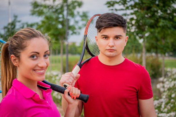 テニス選手は屋外の肖像画。カップルや混合ダブルテニスパートナー最初の外でテニスをプレイ-幸せな若い人たち,女性と男性健康的なアクティブなスポーツライフスタイルを生きています - 写真・画像