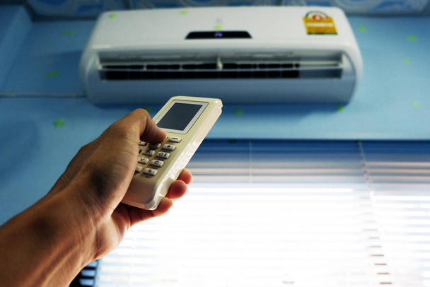 use hand is press remote control for open  air conditioner In the bedroom - Photo, Image