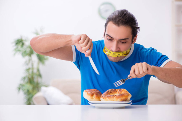 Jonge hongerige man in dieet concept - Foto, afbeelding