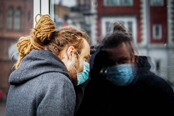 Handsome young European man with a medical face mask on looking inside the pharmacy - Photo, Image